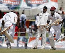 India's bowler Harbhajan Singh, center, watches as West Indies' Shivnarine Chanderpaul, left, and Kirk Edwards, right, run between the wickets during the fourth day of the third cricket Test match in Roseau- AP Photo