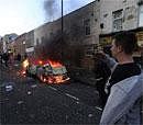 A youth uses his mobile to take a picture of a car burning after it was set on fire by rioters in Hackney, east London on August 8. AP