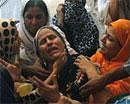 People comfort a woman who lost her son on Friday, Aug 19, 2011 in Karachi, Pakistan. A wave of violence killed many people in Pakistan's largest city, with many of the victims tortured, shot and stuffed in sacks that were dumped on the streets, officials said. (AP Photo