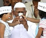 India's anti-corruption activist Anna Hazare drinks coconut water and honey offered by Simran, left, and Ikra to break his fast in New Delhi, India on Sunday. AP Photo