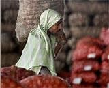 An Indian laborer carries a sack of onions at a wholesale market. AP Photo