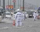 Police officers in rain gear regulate vehicles moving across a flooded national route in Toyokawa, central Japan as powerful Typhoon Roke lashes central Japan with heavy rains and sustained winds of up to 100 mph. AP