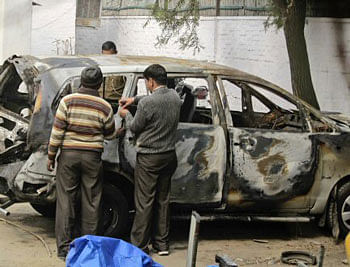 Police officers investigate an Israeli diplomat's car that was damaged in Monday's explosion in New Delhi, India.AP Photo