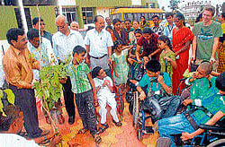 Children pour water on a plant at Snehakiran school for specially-abled children in Mysore on Wednesday. dh photo
