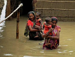 Two women walk through flood water in their inundated Ashigarh village in Morigaon district on Wednesday. PTI