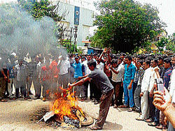 IRE AGAINST BJP: Supporters of Haladi Srinivas Shetty, burn the BJP flag, at Shastri Circle in Kundapur on Friday. (