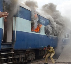 A railways staff member covers his face as he approaches a train car on fire near the Jodhpur railway station in Jodhpur on July 13, 2012.  AFP