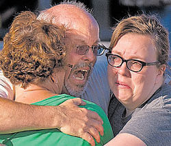 Tom Sullivan, centre, embraces family members outside Gateway High School where he has been searching for his son Alex who went to watch The Dark Knight Rises, where a gunman opened fire on Friday, in Aurora, Colorado. AP