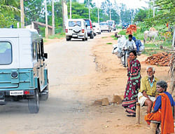 Villagers watch as a convoy of vehicles head to Dharmapura in Hunsur taluk on Saturday.