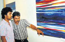 Artist Ronald Pinto explaining his artwork to Radha Kalyana Kannada  tele-serial producer Ashu Bedra at the inauguration of his solo art expo Pearl and the sea at Orchid Art Gallery in Mangalore on Friday.
