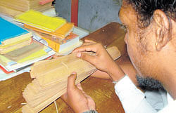 NICHE STUDY: A student examines a palm-leaf  manuscript in Sanskrit.