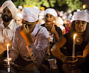 People cover their heads at a candle light vigil in Oak Creek, Wis., Tuesday Aug. 7, 2012, for the victims of a mass shooting at the Sikh Temple of Wisconsin on Sunday. The vigil was held during the national night out event at the Oak Creek Civic Center. AP