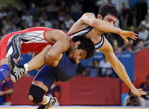 India's Amit Kumar, red, and Iran's Hassan Sabzali Rahimi, blue, compete during a 55-kg men's freestyle wrestling competition at the 2012 Summer Olympics, Friday, Aug. 10, 2012, in London. (AP Photo/Paul Sancya)