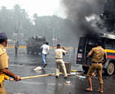Police chasing away demonstrators near a torched vehicle outside CST Station after a protest against Assam riots turned violent in Mumbai on Saturday. PTI