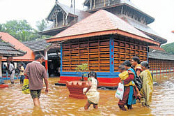 Rain effect: With the rise in water-level in Madhuvahini stream, water had entered Madhur Sri Madanantheshwara Siddivinayaka temple, at Kasargod on Sunday. The devotees are seen walking on the knee-level water in the temple premises.