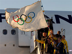 Rio de Janeiro's Mayor Eduardo Paes, top left, Carlos Arthur Nuzman, President of the Brazilian Olympic Committee, bottom right, and Brazilian athletes hold up the Olympic flag upon its arrival in Rio de Janeiro, Brazil, Monday, Aug. 13, 2012. The flag's arrival marks the official start of Rio's Olympic preparations, with the city to undertake nearly 200 projects to construct sports venues and other infrastructure during the next four years. (AP Photo