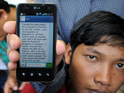 An Assam person showing SMS message at North East people gather to meet CM, for protection from impending violence (on rumours drive North East people out of City since Wednesday), at CM's home office Krishna in Bangalore on Thursday. DH Photo
