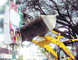 Restoring sense: Municipal authorities tear down illegal banners put up in public areas  during a drive on Friday. DH Photo