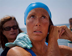 U.S. swimmer Diana Nyad adjusts her swimming cap as a woman applies a protective ointment to her skin as she prepares to jump into the water and start her swim to Florida from Havana, Cuba. Endurance athlete Nyad launched another bid Saturday to set an open-water record by swimming from Havana to the Florida Keys without a protective shark cage. AP Photo
