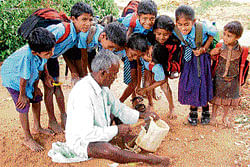 Children watch with curiosity while Hullappa, the carpenter of Kithandur in Srinivaspur taluk, shows his trade. dh photo