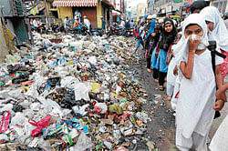 hellhole: Students walk past heaps of garbage in Shivajinagar. dh photos