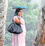 A woman uses a file to protect herself from rain in City on Monday. DH Photo