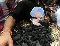 Activists from India's main opposition Bharatiya Janatha Party (BJP) youth wing holds a basket of coal and picture of Indian Prime Minister Manmohan Singh during a protest against the coal allocation controversy of the incumbent government in New Delhi on August 29, 2012. The BJP is demanding that Prime Minister Singh resign over allegations that his government missed out on billions of dollars of revenue by giving away coal rights. AFP