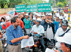 Eco-drive: Additional commissioner at the office of regional commissioner K&#8200;M&#8200;Chandre&#8200;Gowda distributes pamphlets to vehicle riders even as the students hold placards at Ramaswamy&#8200;Circle, in a campaign against wasting fuel, in Mysore on Friday. ACP (traffic)&#8200;Shankare&#8200;Gowda is also seen. DH Photo