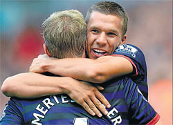 ON&#8200;SONG Arsenal's Lukas Podolski hugs team-mate  Per Mertesacker after scoring against Liverpool in the  English Premier League on Sunday. AFP