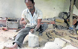 A person busy chiseling a grinding stone in Jagiru Bane in Paluru Village.