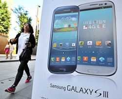 A woman walks past a signboard of Samsung Galaxy S3 at a mobile phone shop in Seoul AFP