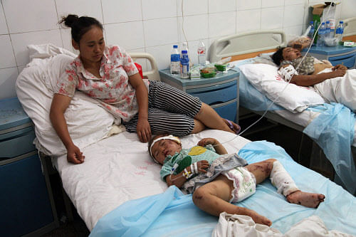 A woman watches over her injured child on a bed in a hospital in Yiliang on September 8, 2012, after two quakes hit on the border of southwestern Yunnan and Guizhou provinces an hour apart on September 7. At least 80 people were killed in the series of earthquakes that hit a remote and mountainous area of southwest China, the Xinhua news agency quoted the government as saying on September 8.