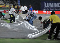 Indian groundsmen cover the pitch during a heavy rain prior to start of the first Twenty20 cricket match between India and New Zealand at Dr. Y.S. Rajasekhara Reddy Cricket Stadium in Visakhapatnam on September 8, 2012. AFP