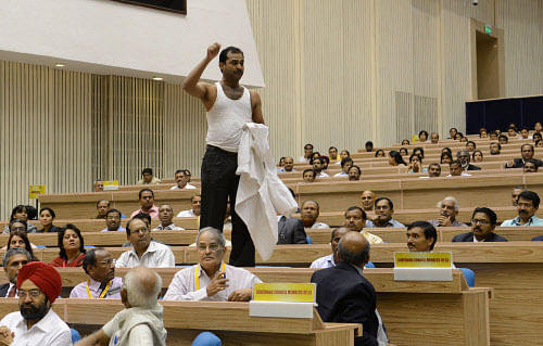 A demonstrator, stripped to his undershirt while standing on top of a table, shouts slogans in protest before a speech by Prime Minister Manmohan Singh in New Delhi on September 22, 2012.  AFP