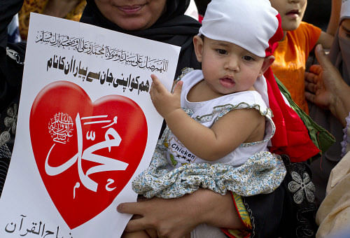 A baby girl plays with a placard that reads 'the name of Muhammad is dear to us than anything,' as she is held by her mother as she participates in a demonstration that is part of widespread anger across the Muslim world about a film ridiculing Islam's Prophet Muhammad, Saturday, Sept. 22, 2012 in Islamabad, Pakistan.