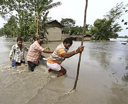 Villagers cross a flooded road at Lachi Bishnupur village in Assam September 22, 2012.  Credit: Reuters