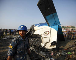 A Nepalese police officer stands in front of the wreckage of a Dornier aircraft, owned by private firm Sita Air, at the crash site in Kathmandu September 28, 2012. A small plane crashed shortly after takeoff from the Nepali capital of Kathmandu on Friday, killing 19 people, including seven British and five Chinese passengers, an airline official said. REUTERS