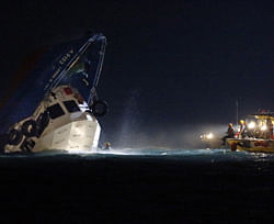 Rescuers check on a half submerged boat after it collided Monday night near Lamma Island, off the southwestern coast of Hong Kong Island Tuesday, Oct. 2, 2012. Authorities in Hong Kong have rescued 101 people after a ferry collided with a tugboat and sank.  AP