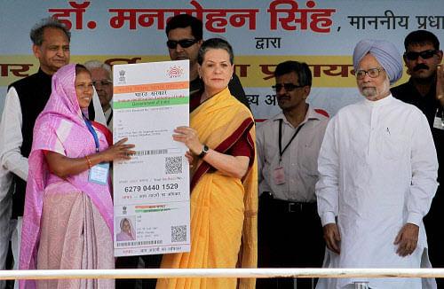 Jaipur: Prime Minister Manmohan Singh looks on as UPA Chairperson Sonia Gandhi delvers 21st crore Aadhar card to a woman during launch of 'Aadhaar Enabled Service Delivery' on the 2nd anniversary of Adhaar Card at Dudu near Jaipur on Saturday. PTI Photo