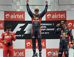 Winner Red Bull-Renault driver Sebastian Vettel of Germany (C) jumps at the podium with third-placed teammate Red Bull-Renault driver Mark Webber of Australia (R) and second-placed Ferrari driver Fernando Alonso of Spain (L) after victory at the Formula One Indian Grand Prix at The Buddh International circuit in Greater Noida, on the outskirts of New Delhi on October 28, 2012. AFP PHOTO