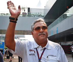 Force India team principal and businessman Vijay Mallya waves as he walks down the F1 paddock after the third practice session for the Indian Formula One Grand Prix at the Buddh International Circuit in Noida, on the outskirts of New Delhi, India, Saturday, Oct. 27, 2012. AP