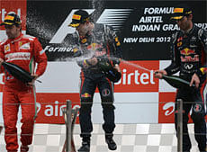 Winner Red Bull-Renault driver Sebastian Vettel of Germany (C) is sprayed champagne by third-placed teammate Red Bull-Renault driver Mark Webber of Australia (R) while second-placed Ferrari driver Fernando Alonso of Spain looks on after victory at the Formula One Indian Grand Prix at The Buddh International circuit in Greater Noida on Sunday. PTI Photo