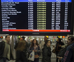 Travellers surround a flight monitor showing cancelled flights at LaGuardia airport in New York October 28, 2012. Tens of millions of East Coast residents scrambled on Sunday to prepare for Hurricane Sandy, which could make landfall as the largest storm to hit the United States, bringing battering winds, flooding and even heavy snow. REUTERS