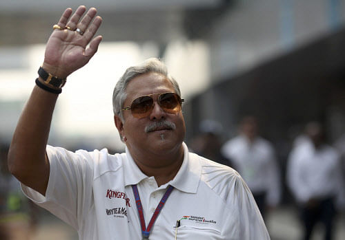 Force India team principal Vijay Mallya waves in the paddock during the third practice session of the Indian F1 Grand Prix at the Buddh International Circuit in Greater Noida, on the outskirts of New Delhi, October 27, 2012. Embattled Mallya made his Indian Grand Prix entrance in combative mood on Saturday, lashing local media for their coverage of his business troubles and grounded Kingfisher airline. The liquor and aviation tycoon, no longer a billionaire according to the latest Forbes list, flew in from London on his private Airbus after suggestions that he might stay away to avoid having it impounded. REUTERS