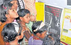 Children eagerly glance at posters and photographs of child rights displayed in the expo held at Dasara Exhibition grounds in Mysore on Thursday . dh photo