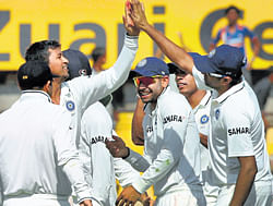 spin twins: Pragyan Ojha exchanges high fives with fellow spinner R Ashwin after claiming an England wicket. PTI