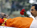 Uddhav Thackeray, son of Bal Thackeray carries flowers past his body during his funeral in Mumbai on Sunday. PTI