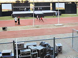 IN A MESS: Athletes train as workers prepare the stage at the Sree Kanteerava stadium    for a corporate event to be held on&#8200;Sunday. DH PHOTO