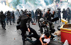 Policemen kick a protester during their clash in Bangkok on Saturday. AP