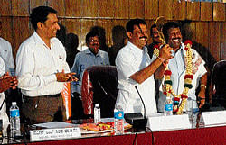 District-in-Charge Minister Appachu Ranjan felicitates Minister for Social Welfare A Narayana Swamy by offering traditional Odikathi, before the commencement of review meeting in Madikeri on Tuesday. Social Welfare Department Commissioner Naveen Raj Singh among others looks on.